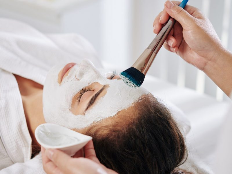 Young woman getting beauty treatment in spa salon and enjoying soothing mask